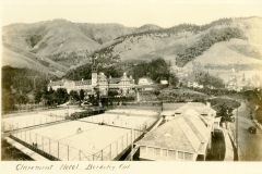 A vintage image of the Claremont Hotel in Berkeley, California, with tennis courts in the foreground and rolling hills in the background. The hotel features a large central tower and intricate architecture.