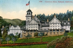 A vintage postcard image of the Claremont Hotel in Oakland, California. The large, elegant building features Tudor-style architecture with a prominent clock tower. An American flag flies atop the tower, surrounded by lush greenery and landscaped gardens.