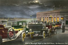 Vintage cars line the street at night outside San Francisco’s iconic Cliff House. Warm lights glow from the building as people gather nearby, framed by a cloudy, moonlit sky in the background.