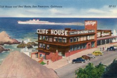 Vintage postcard illustration of San Francisco’s iconic Cliff House restaurant, overlooking the ocean with a large ship in the background, rocky shore, parked cars, and a clear blue sky.