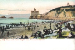 Crowds gather on a beach near the Cliff House in San Francisco, with Sutro Heights rising on the hill. The pastel sky casts a soft glow over the ocean, cliffs, and piers in the background.