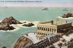 A vintage postcard shows a crowd gathered near San Francisco’s iconic Cliff House overlooking Seal Rocks and the ocean. Waves crash around the rocks, boats dot the distance, and an American flag flies atop the historic building.