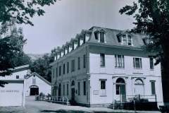 Cohen Hotel, Warm Springs, Alameda Co. California. A black and white photo of a large, three-story building with dormer windows and a gabled roof. Trees frame the scene, and a smaller building is visible to the left with a No Parking sign. The setting is peaceful and historic.