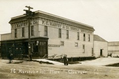 A vintage photo of F.C. Harvey & Co. General Merchandise store in Obrarde, California. The building is wooden with signage and power lines. A horse-drawn carriage and a few people are outside on a dirt road.