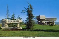 A concrete sign reads Civic Center, City of Fremont on a grassy field with trees. In the background, a modern, blocky building stands against a clear blue sky. The caption below reads Fremont Civic Center.