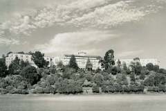 Masonic Home, Union City, California. A historic, multi-story building with a central dome, surrounded by trees, is set against a dramatic sky filled with scattered clouds. The foreground features a wide, open field.