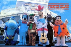 Six people in colorful cartoon character costumes stand in front of a Western-style building at Frontier Village amusement park in San Jose, California. A sign reads “FRONTIER VILLAGE AMUSEMENT PARK” beneath a white saloon with a balcony and railing.