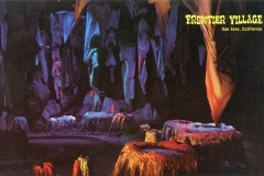 Colorful artificial stalagmites and stalactites fill a dimly lit cave exhibit at Frontier Village in San Jose, California. Yellow text reading FRONTIER VILLAGE San Jose, California appears in the upper right corner.