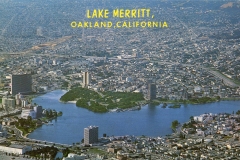 Aerial view of Lake Merritt in Oakland, California. The lake is surrounded by urban buildings and residential areas, with hills in the background. Large text at the top reads Lake Merritt, Oakland, California.