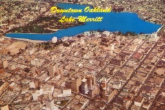 Aerial view of downtown Oakland, featuring Lake Merritt. The cityscape is densely packed with buildings, roads, and greenery surrounding the blue water of the lake. Text on the image reads Downtown Oakland and Lake Merritt.