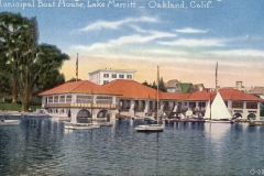 A vintage postcard depicts the Municipal Boat House at Lake Merritt in Oakland, California. It features sailboats near the boathouse with a red-tiled roof and arched windows, set against a backdrop of trees and a clear sky.