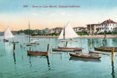 Vintage postcard depicting sailboats and rowboats on Lake Merritt, Oakland, California. The scene includes calm water, a clear sky, and elegant buildings along the shoreline, with text reading 3009 - Scene on Lake Merritt, Oakland, California.