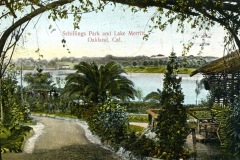 Vintage postcard of Schillings Park and Lake Merritt in Oakland, California. The scene features a winding path, lush greenery, trees, and a calm lake in the background, with structures visible across the water.