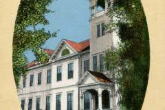 A vintage postcard features a historic high school building in Livermore, California. The structure is three stories tall with a prominent clock tower, surrounded by trees and shrubbery. The sky is clear and blue.