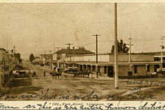 Sepia-toned photo of a street in Livermore, CA, dated August 25, 1905. Shows horse-drawn carriages and wooden buildings. A handwritten note reads, You see this is not a very large town, as this is the entire business district.