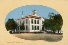 A vintage illustration of a large, two-story building labeled Grammar School, Livermore, Cal. The building features a central tower, tall windows, and is surrounded by trees, set against a blue sky backdrop.