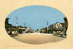 Vintage postcard depicting Main Street in Livermore, California, looking east. The street is bordered by old-fashioned wooden buildings and telephone poles under a clear blue sky.