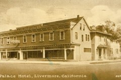 Sepia-toned vintage photo of Palace Hotel, a two-story building with a large sign, in Livermore, California. Adjacent is a residential house. The street is empty, creating a nostalgic early 20th-century atmosphere.