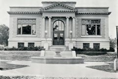 Black and white photo of Public Library, Livermore published in 1914. The architecture features large windows, columns, and a central entrance with steps leading to a doorway, surrounded by landscaped grounds.