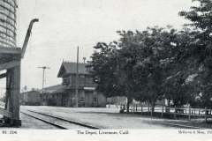 A vintage black-and-white photograph of The Depot in Livermore, California. The image shows the train tracks leading to a small station building surrounded by trees. The scene appears quiet and historic, with old-fashioned architecture.