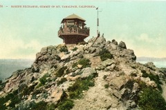 Historic photo of Marine Exchange lookout at the summit of Mt. Tamalpais, California. The wooden structure sits atop a rocky peak with surrounding vegetation, under a clear sky.