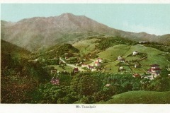 A vintage postcard depicts a scenic view of Mt. Tamalpais. Lush green hills are dotted with houses and trees, under a clear sky. The mountain looms majestically in the background. Text on the bottom reads Mt. Tamalpais.