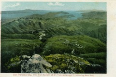 A vintage postcard depicts a view from the summit of Mt. Tamalpais, revealing winding roads amidst lush green hills, with San Francisco Bay visible in the background. The image includes text labeling the location.