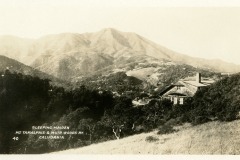 Black and white photograph of Mount Tamalpais, labeled Sleeping Maiden, Mt. Tamalpais & Muir Woods Ry. California. The foreground features trees and a house, with a mountain range in the background under a clear sky.