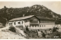 Black and white photograph of the Mt. Lowe Tavern on Mt. Tamalpais, California. The building sits on a hillside, surrounded by trees, with a few smaller structures higher up the hill. Text on the photo describes its elevation.