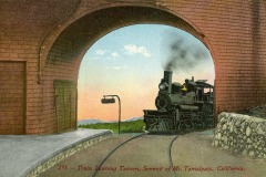 A vintage train exits a tunnel at the summit of Mount Tamalpais in California. The sky is colorful, indicating either sunrise or sunset, and the surrounding landscape is visible under the tunnel arch. The text reads Train Leaving Tavern, Summit of Mt. Tamalpais, California.