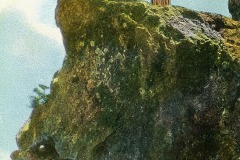 Two people stand on the edge of the Overhanging Rock on Mt. Tamalpais, Marin County, California. The man gestures outward, while the woman stands beside him. The photo has a vintage, postcard-like appearance.