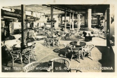 Historic photo of Nut Tree patio in Vacaville, California, featuring round wicker tables and chairs arranged under a pergola. Hanging and potted plants are visible, with the text marking the location along U.S. Highway 40.
