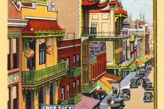 A vintage postcard illustration of Chinatown in San Francisco. The street is lined with colorful, ornate buildings featuring traditional Chinese architectural elements. Classic cars are parked along the road, and Chop Suey signs are visible.
