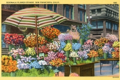 A vintage postcard features a bustling San Francisco sidewalk flower stand. The vibrant display includes a variety of colorful bouquets under a striped umbrella, set against an urban backdrop with historic buildings.