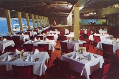 Sea Wolf Restaurant, nestled in Jack London Square, is a spacious and elegant dining spot. Red chairs surround tables adorned with white tablecloths and folded napkins. Large windows offer sea views, allowing natural light to flood the room, while an aquarium adds to its charm.