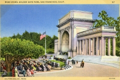 A vintage postcard shows a bandstand in Golden Gate Park, San Francisco. People sit and stand, watching a performance. An American flag flutters nearby. The structure is grand with columns and trees surround the area.