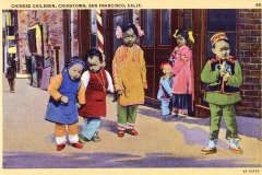 A vintage postcard showing six children in colorful traditional clothing standing on a street in Chinatown, San Francisco. The children are gathered near a brick building, with four standing and two bending forward.