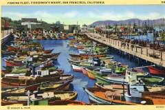 Colorful vintage postcard of the fishing fleet at Fishermans Wharf, San Francisco. Numerous boats of various colors docked along a bustling pier with people, against a backdrop of hills and a clear sky.